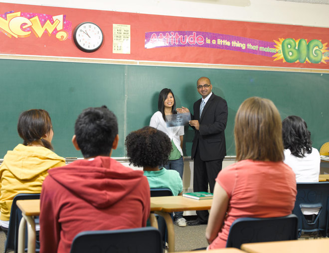 2 teachers standing in front of a classroom of youth