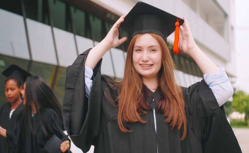 High school student posing for graduation photo in cap and gown. 