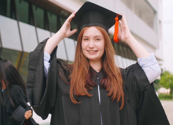 High school student posing for graduation photo in cap and gown. 