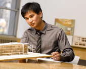 Architect in an office looking at a wooden model of a building