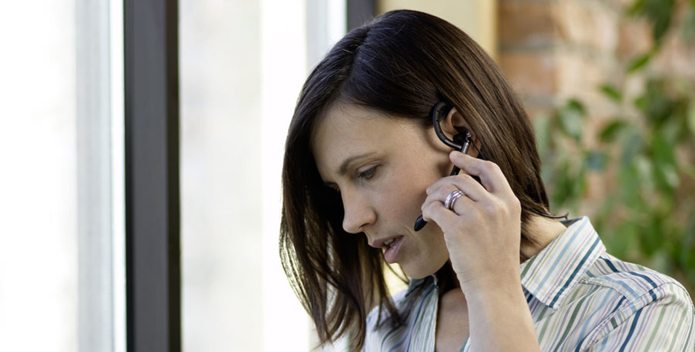 Person talking on the phone using a headset while looking at documents