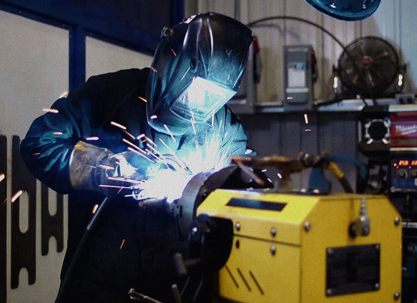 Worker with helmet down welding in a shop
