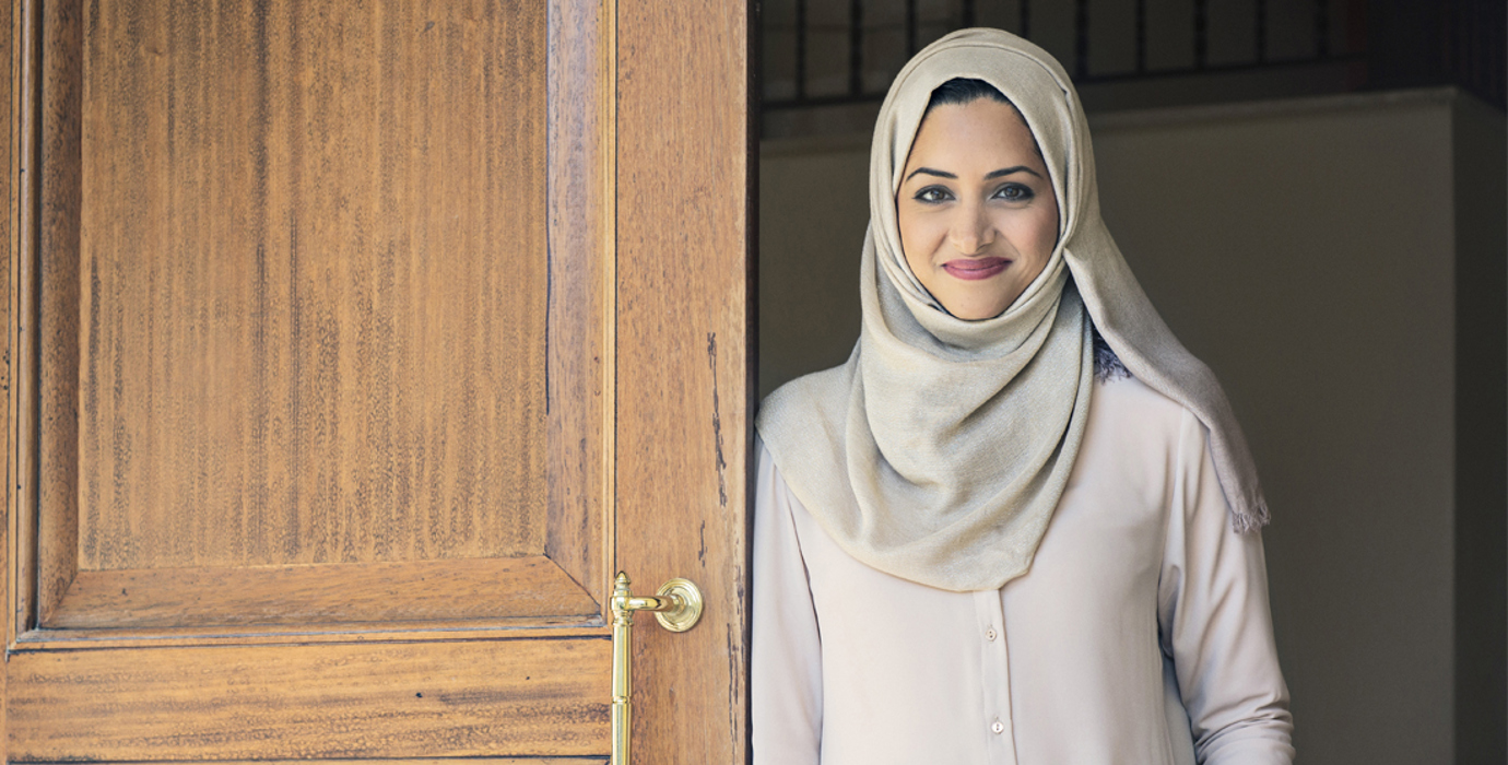 Person smiling while leaning against an open door