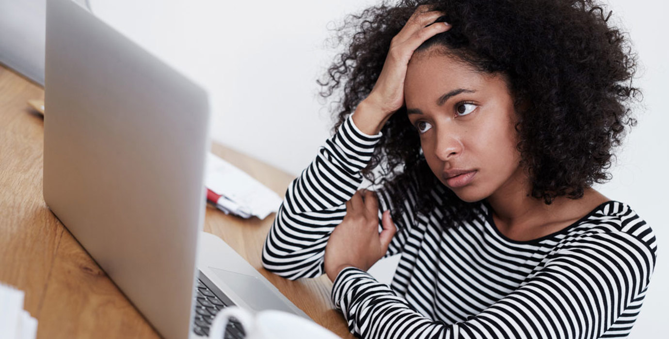 Frustrated person holding head in hand looking at computer