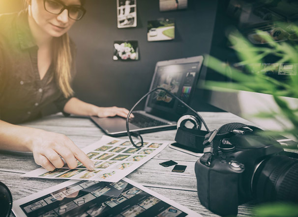 Person reviewing photographic proofs with laptop and DSLR camera