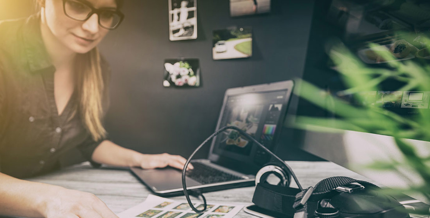 Person reviewing photographic proofs with laptop and DSLR camera