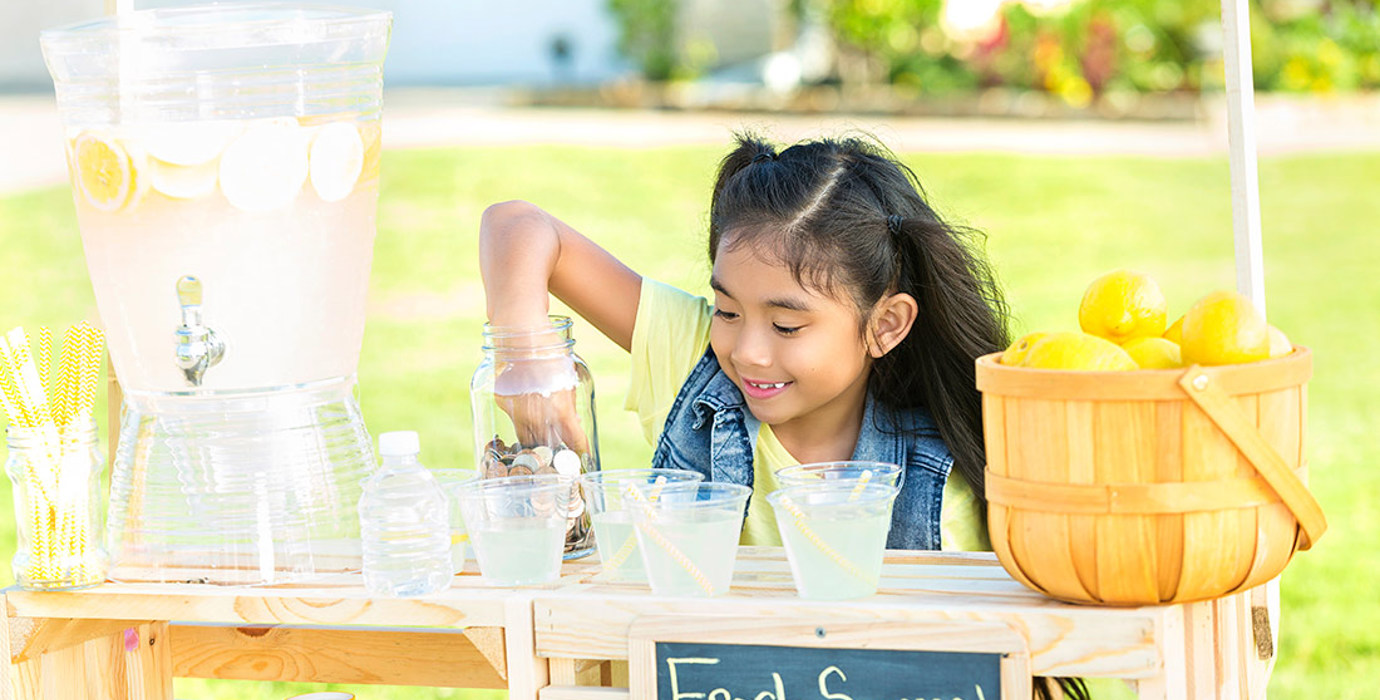 Youth picking coins out of a jar at a lemonade stand