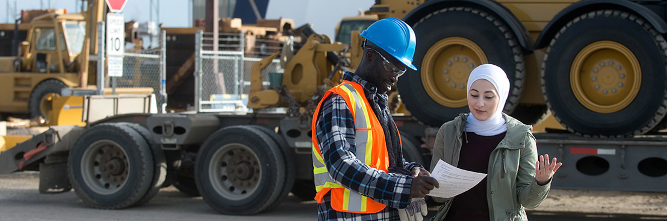 Employees on a jobsite having a discussion in front of large equipment