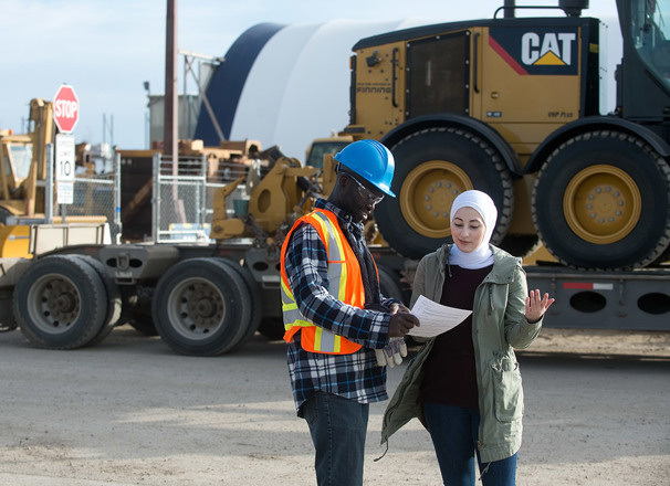 Employees on a jobsite having a discussion in front of large equipment