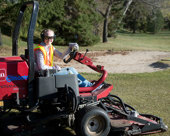 Golf course groundskeeper riding the mower