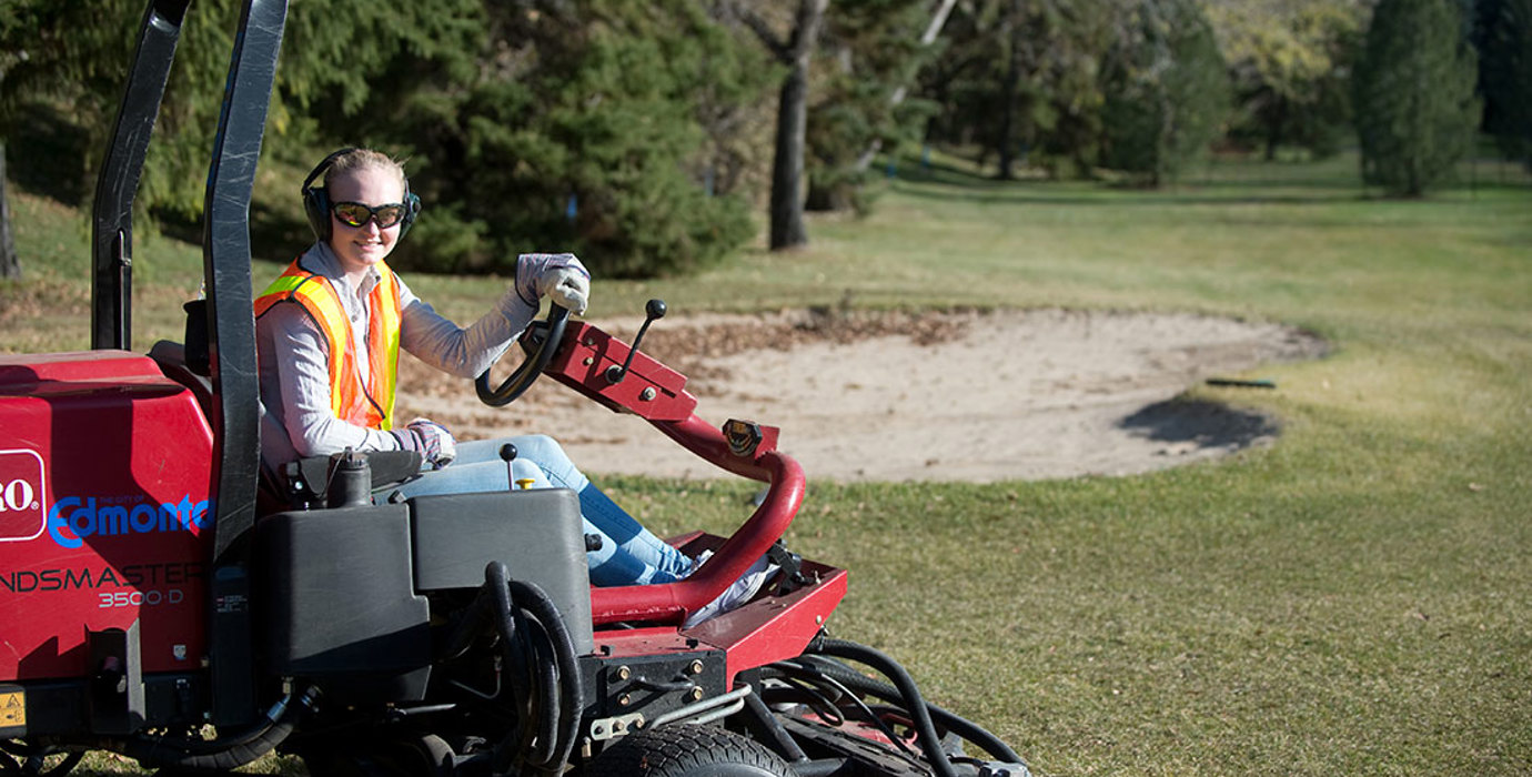 Golf course groundskeeper riding the mower