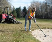 Golf course groundskeeper working on a sand bunker