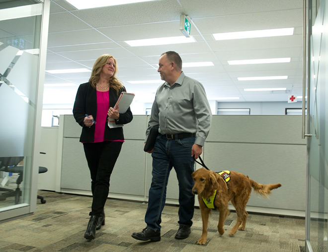 Employee with service dog talking with another employee in the office
