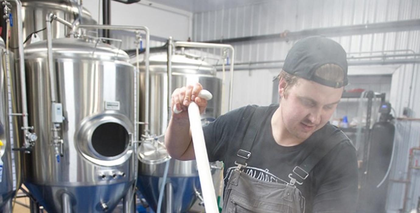 Entrepreneur in a brewery mixing ingredients in brewing tank