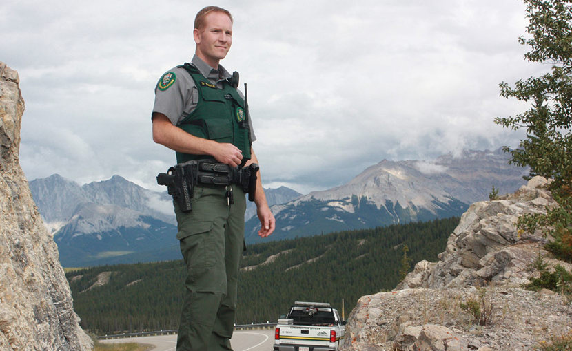 Conservation officer standing on a rock with mountains in the background