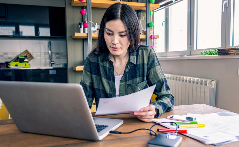 Person working at home with laptop and paper