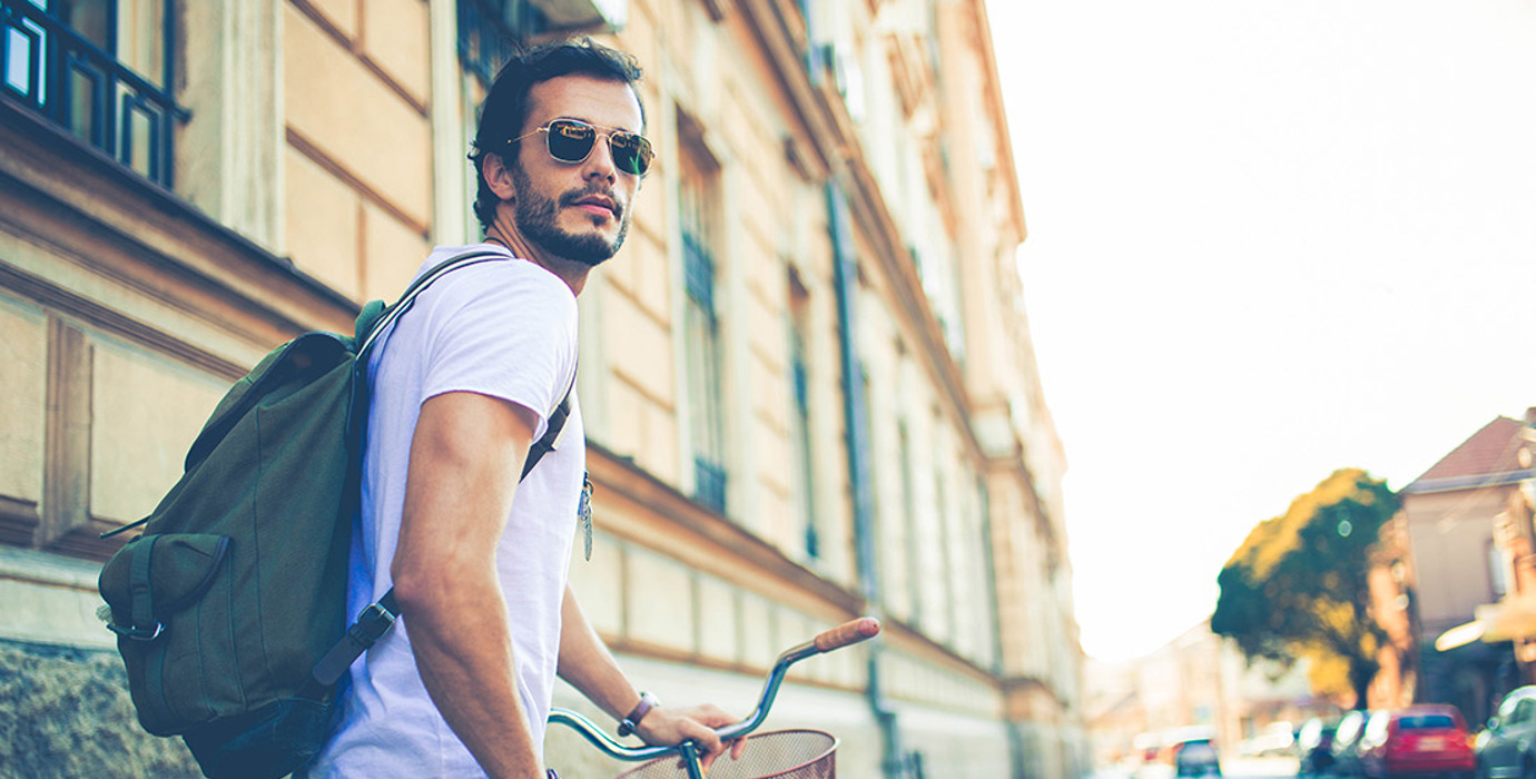 Student walking a bike on a city sidewalk