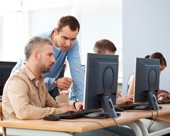 Mature student and teacher talking in a computer lab