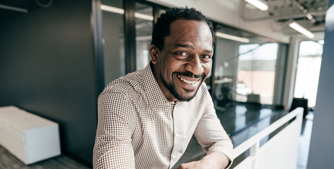 Person smiling into the camera leaning on a balcony railing