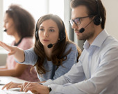 2 people wearing headsets having a discussion in front of a computer