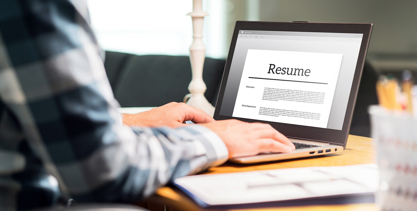 Hands typing on a laptop with the screen showing a resume