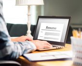 Hands typing on a laptop with the screen showing a resume