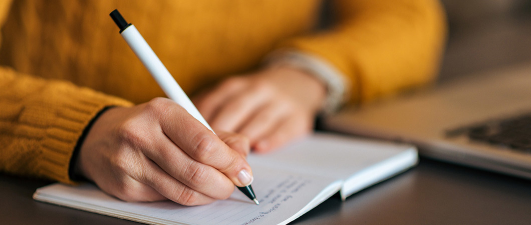 Closeup of person writing in a notebook with a pen