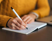 Closeup of person writing in a notebook with a pen