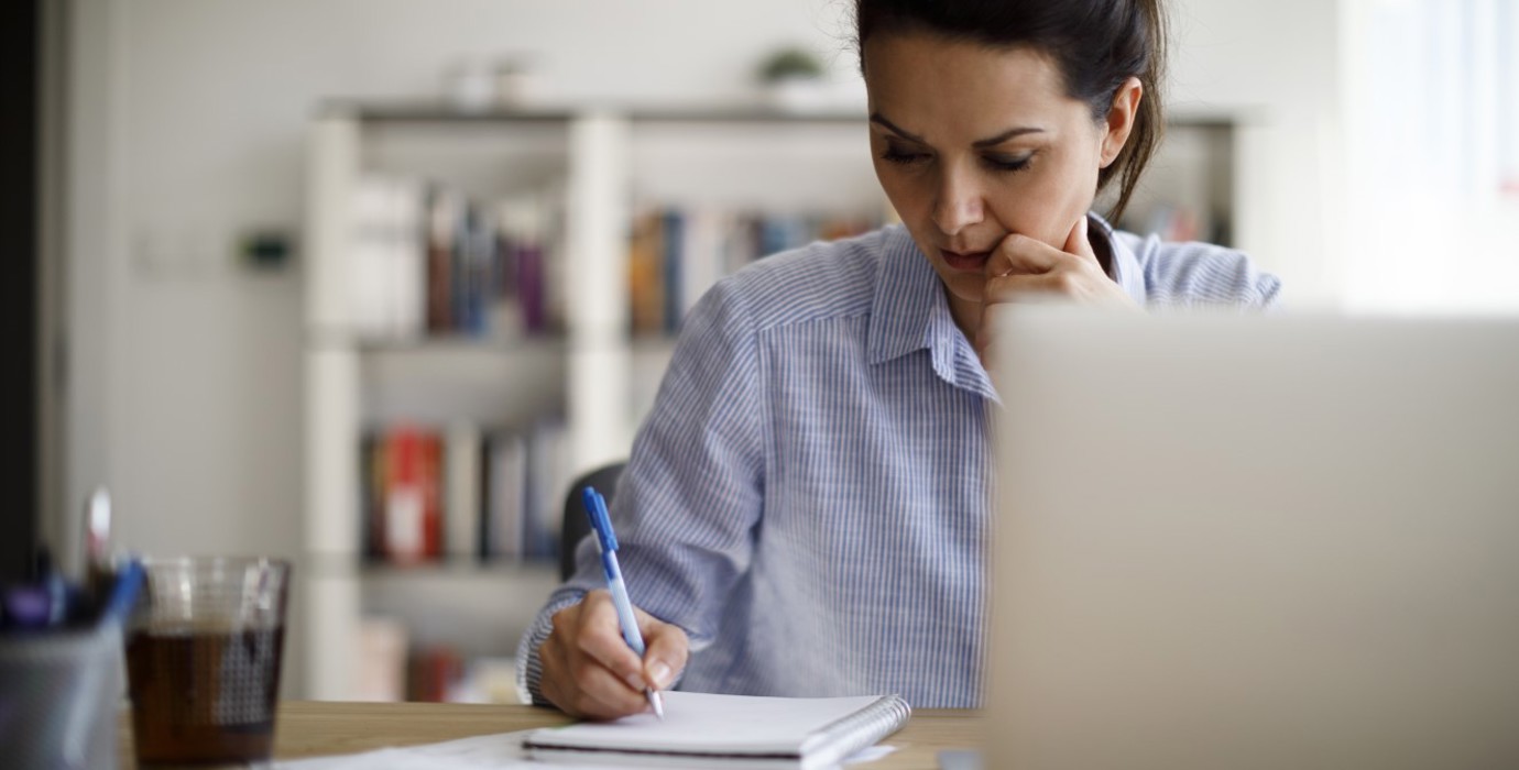 Person writing in a notebook at a desk