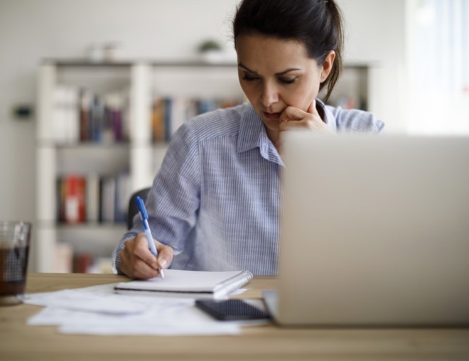 Person writing in a notebook at a desk