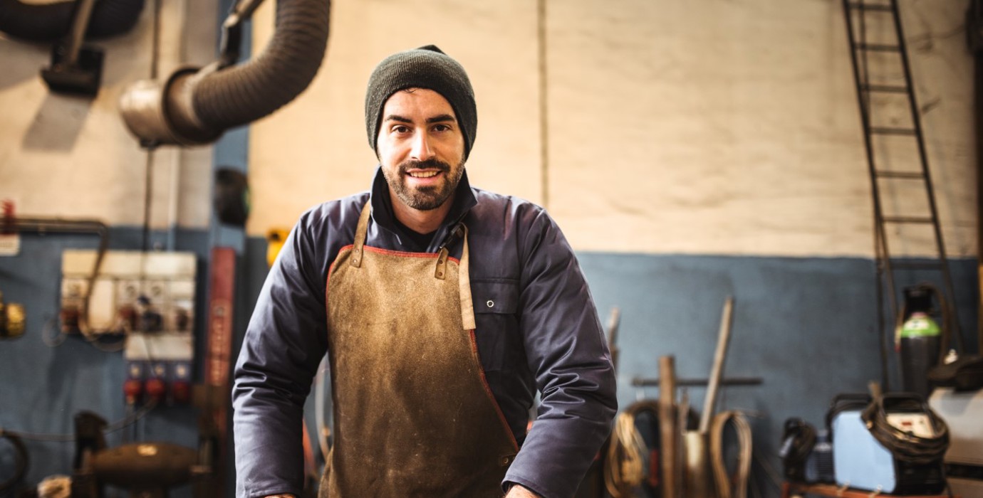 Worker wearing gloves and an apron standing in a workshop