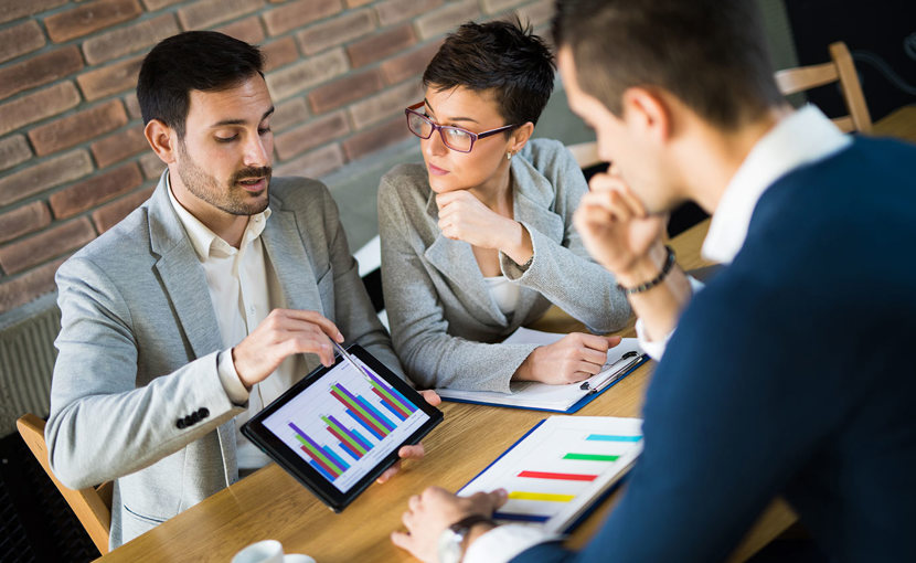 Biostatistician pointing to a graph on a tablet and discussing with coworkers