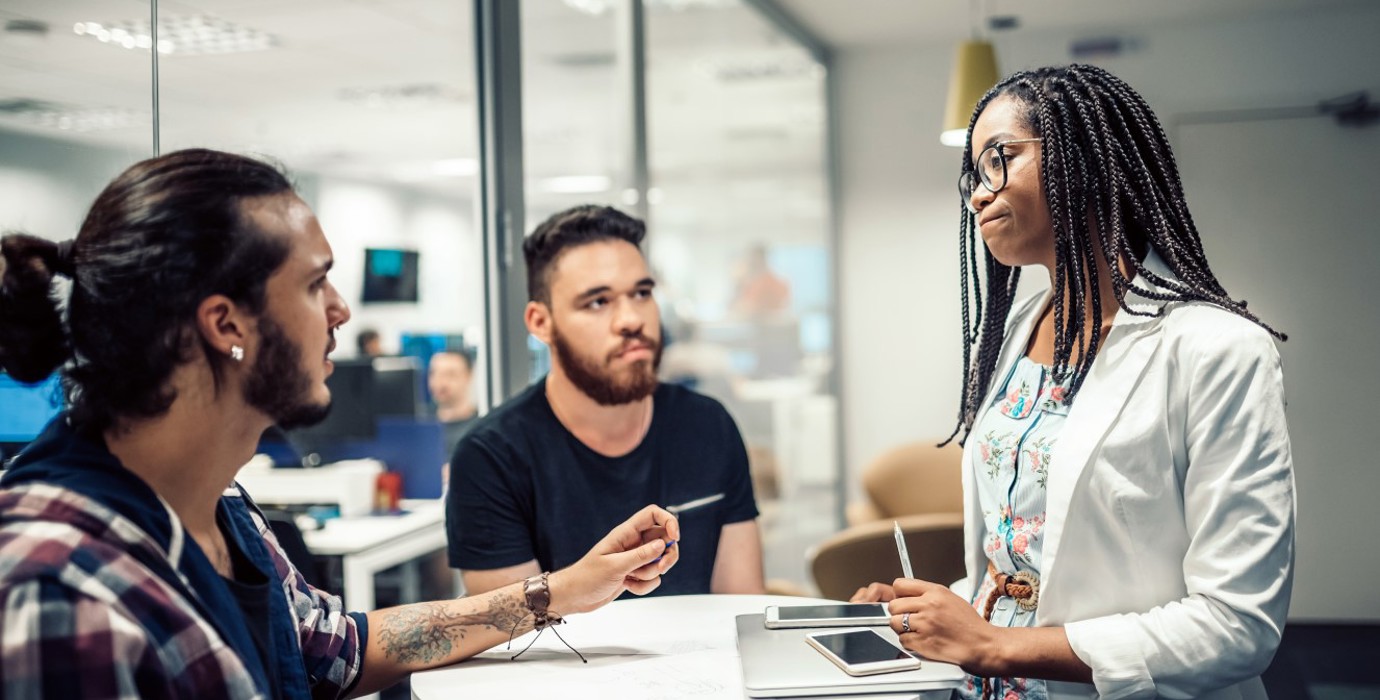 Three coworkers having a disagreement in a meeting room.