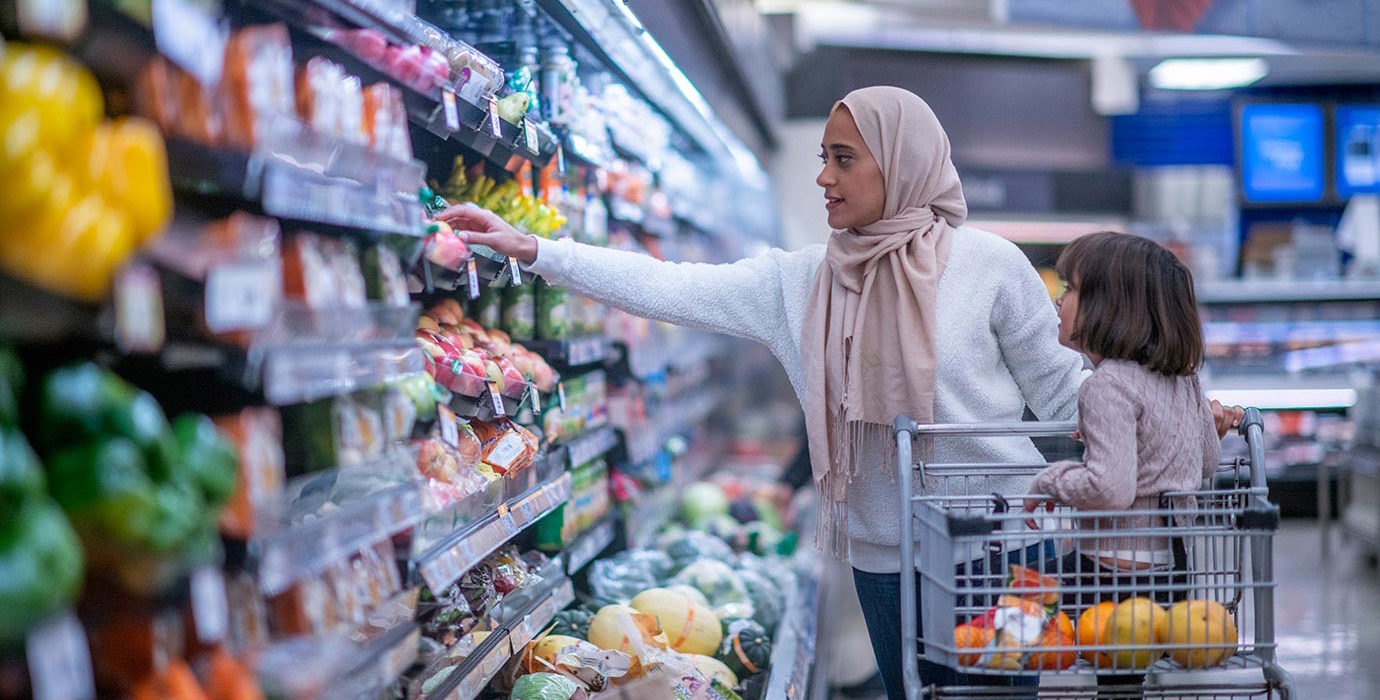 Woman grocery shopping with child in the shopping cart.