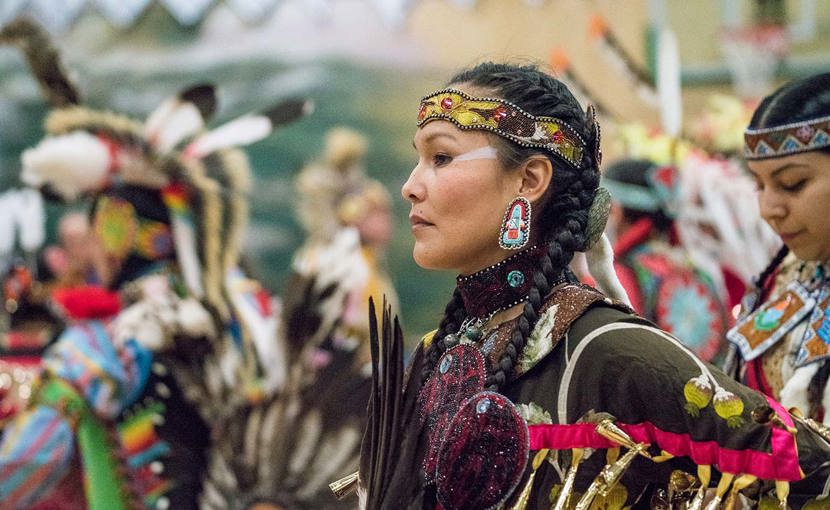 A dancer from Semiahmoo First Nation wearing traditional clothing pauses during a pow wow.