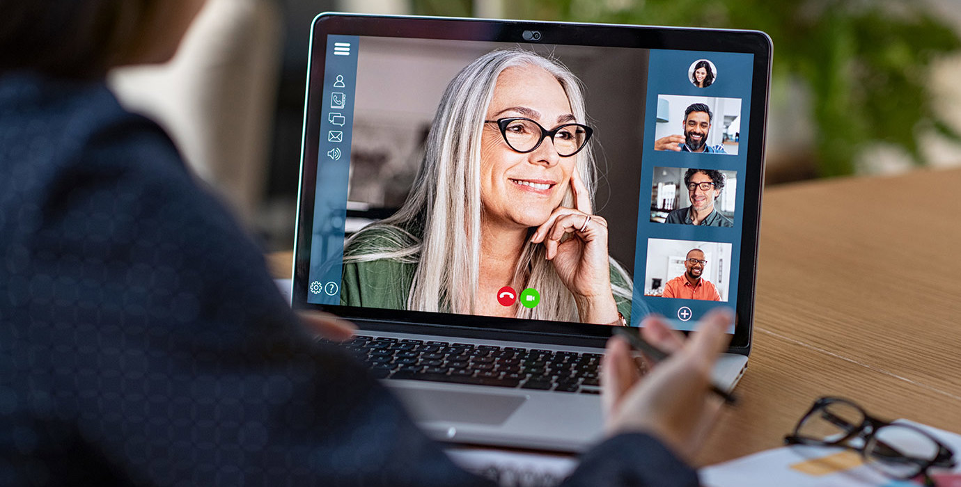 A laptop screen shows a video conference.