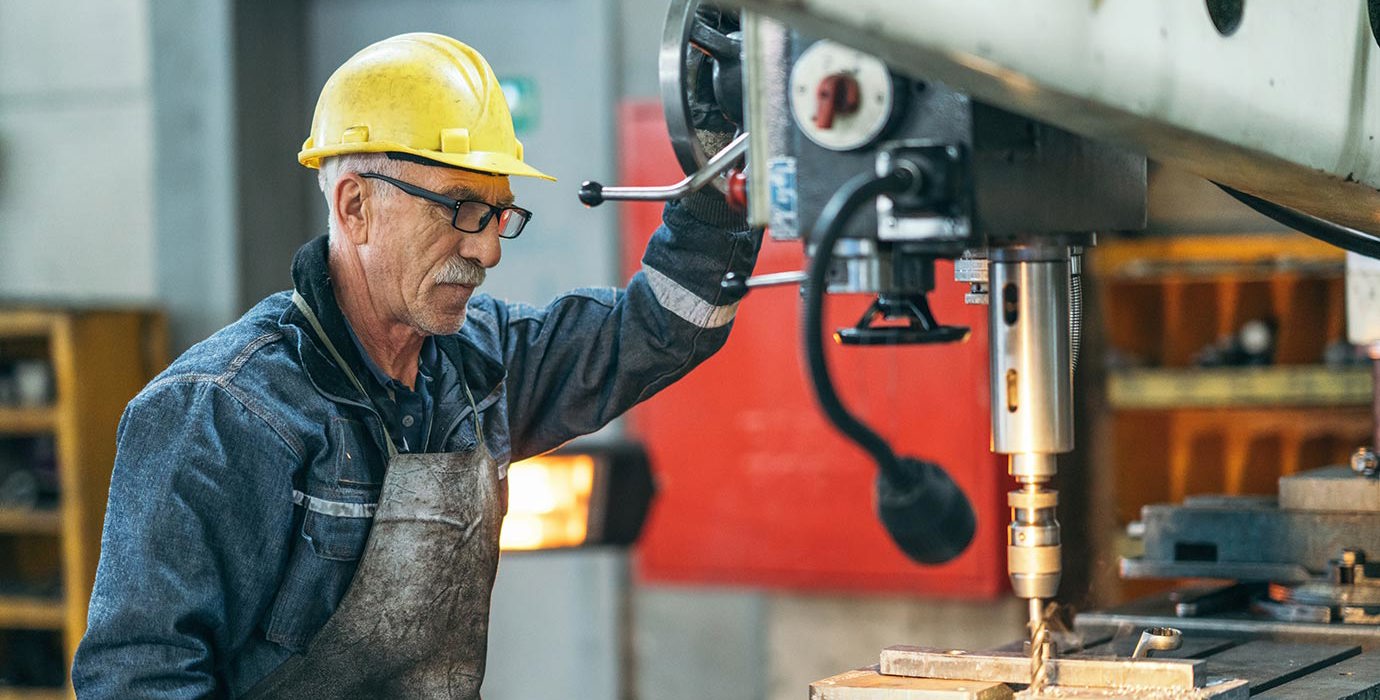 A machinist works with a drill bit in a workshop.