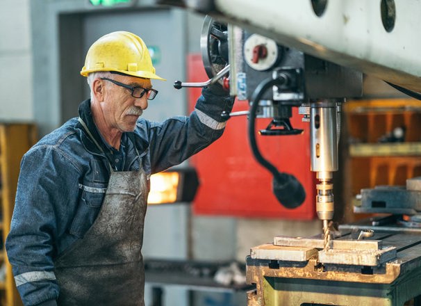 A machinist works with a drill bit in a workshop.