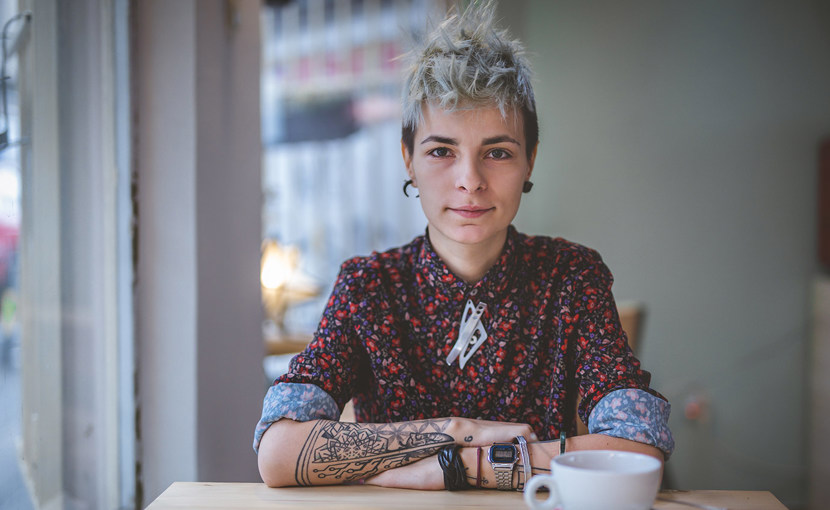 A portrait of a person sitting at a cafe table.
