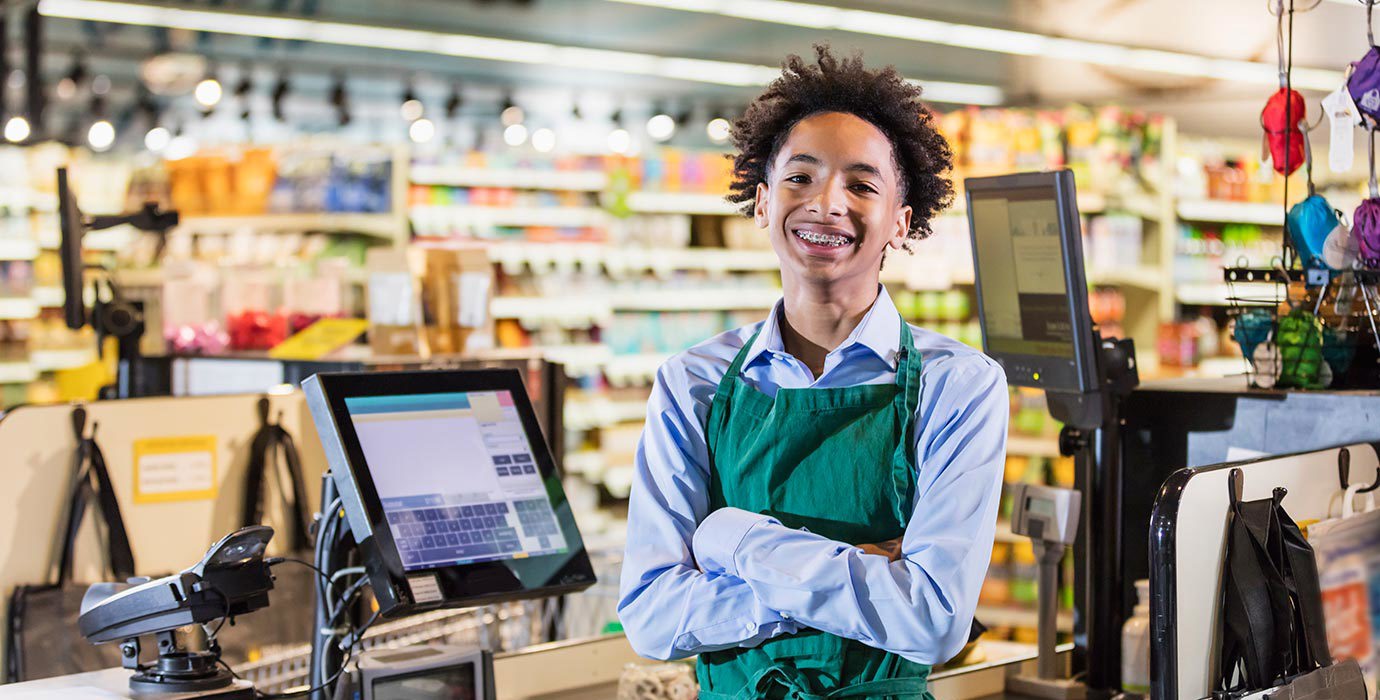 A portrait of a young cashier at a grocery store.