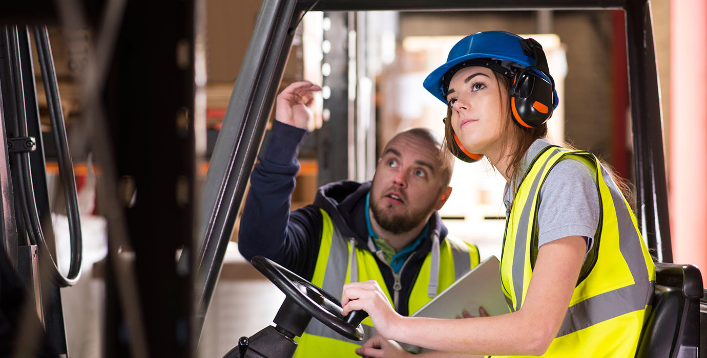 A forklift driver trains with another worker.
