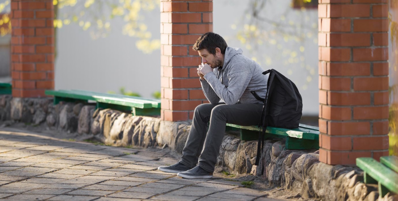 Mature student sitting anxiously outside of school.
