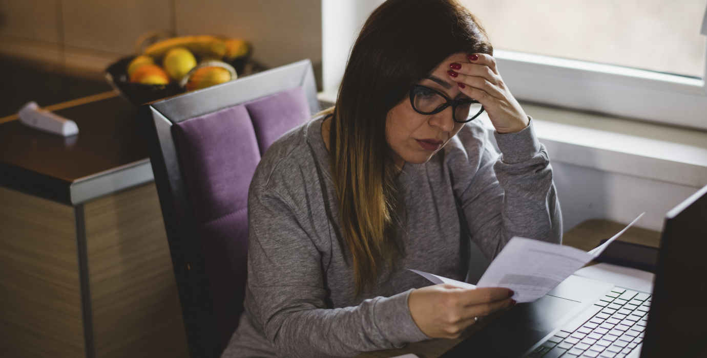 Concerned looking person reviewing a paper at their desk.