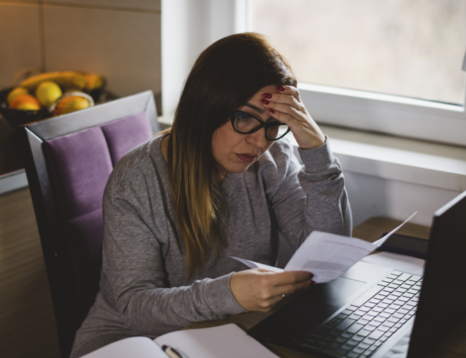 Concerned looking person reviewing a paper at their desk.