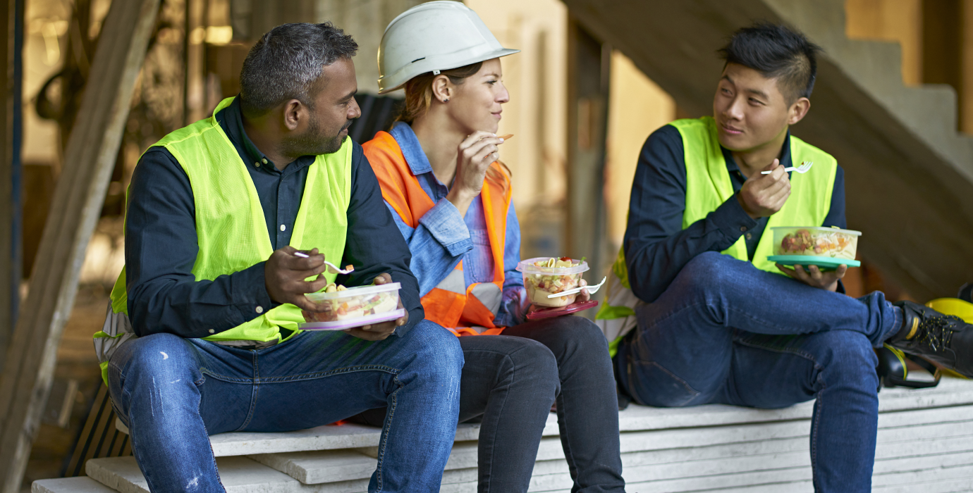 Three construction workers eating lunch on a jobsite.