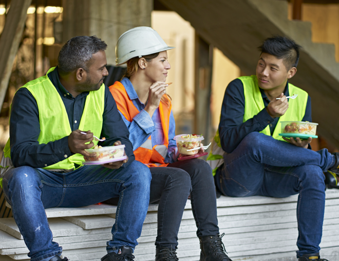 Three construction workers eating lunch on a jobsite.