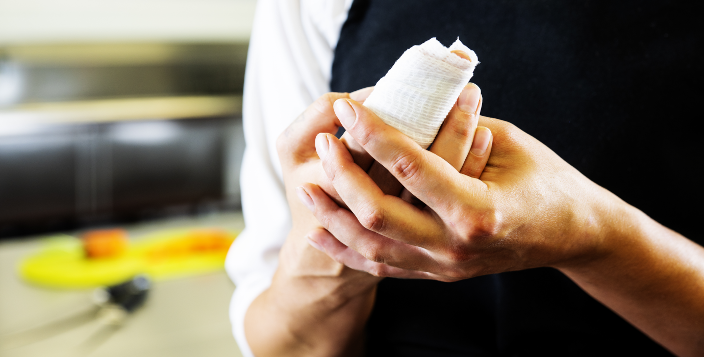 Chef holding injured finger in kitchen.