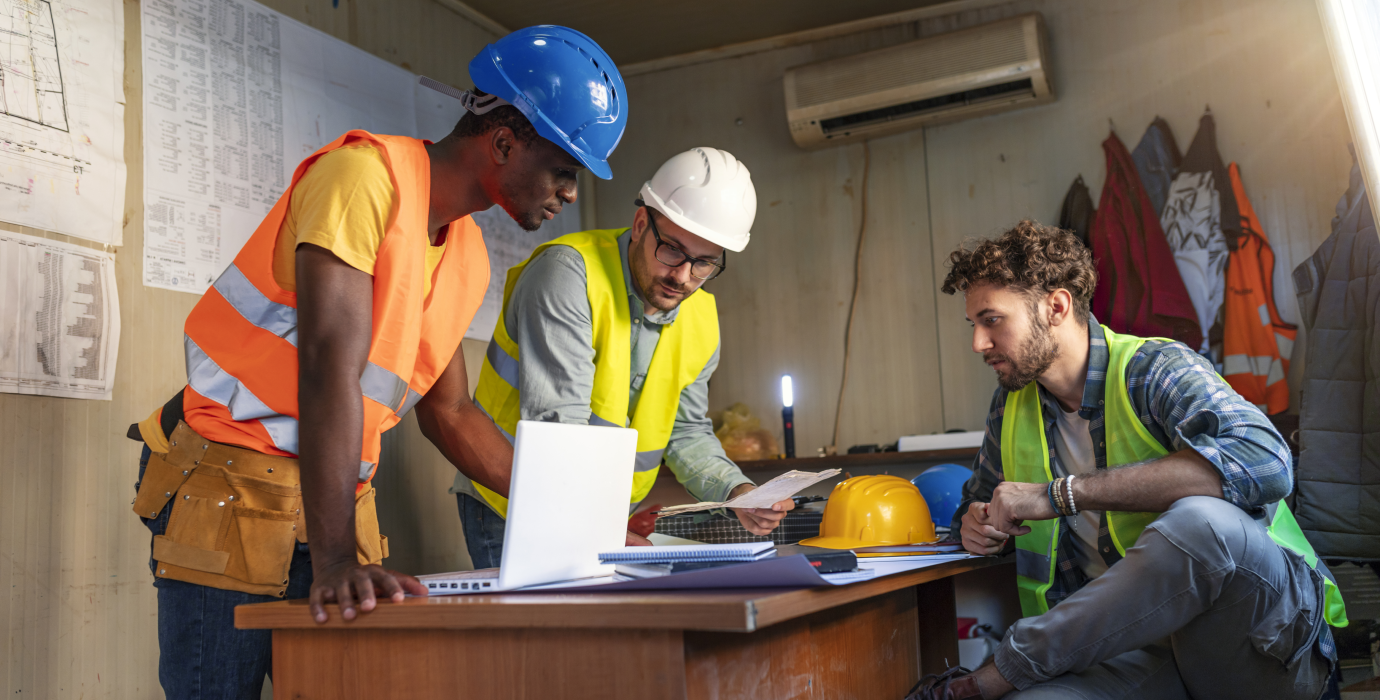Workers around desk discussing project plans.