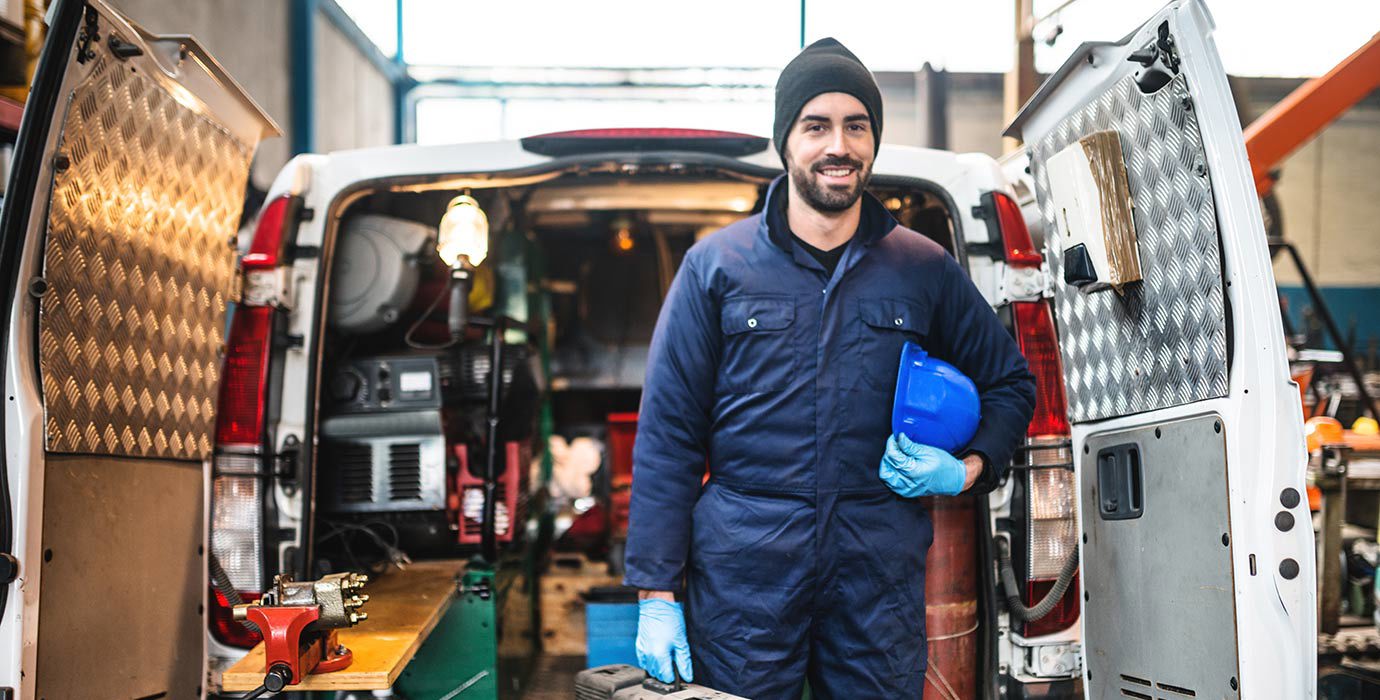 Mechanic standing in front of the opened back doors of a van