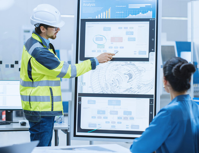 Person wearing PPE making a report at a meeting